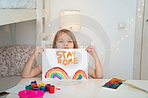 Little girl drew rainbow and poster stay home.