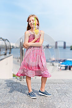 Little girl drinking fruit cocktail outdoors in the summer day.