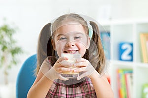 Little girl drinking milk from glass indoor