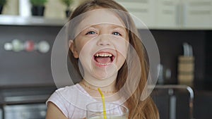 Little girl drinking milk through a straw from a glass