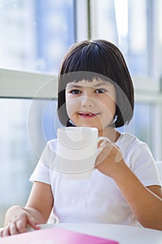 Little girl drinking tea of milk at home