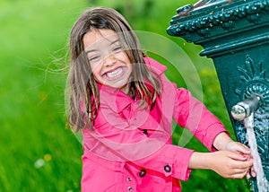 Little girl drinking water in a fountain