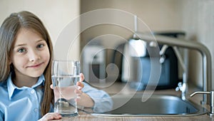 Little girl drinking from water tap or faucet in kitchen. Pouring fresh drink. Healthy lifestyle. Water quality check concept. Wor