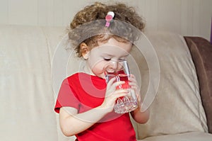 Little girl drinks clean spring water from glass. child quenches thirst with aqua at home