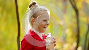 Little girl drinks clean water in the outdoors. Little girl drinks clean water in autumn Park. Healthily concept. Healthy