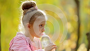 Little girl drinks clean water in the outdoors. Little girl drinks clean water in autumn Park. Healthily concept. Healthy