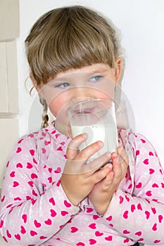 The little girl drinks milk, the benefits of milk and calcium for children. A child of three years.