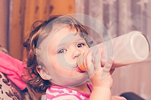 Little girl drinks milk from a bottle