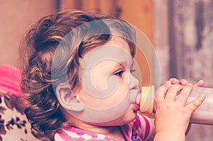 Little girl drinks milk from a bottle