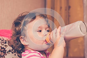 Little girl drinks milk from a bottle