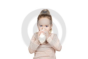 Little girl drinks milk from a glass isolated on white