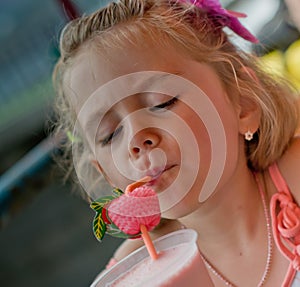 Little girl drinks milk shake in cafe