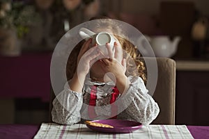 Little girl drinks tea from a large cup