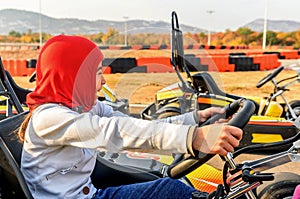 Little girl is driving Go- Kart car in a playground racing track