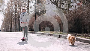 The little girl is driving a scotter on a park alley