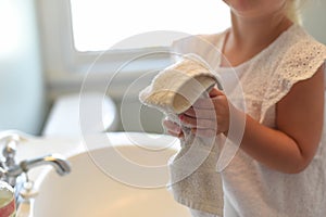 Little girl drying hands on a towel in bright morning light