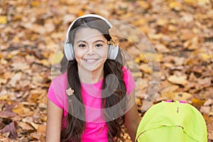 Little girl in earpieces with backpack, autumn