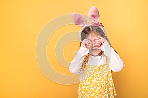 Little girl with ears of a hare holds painted eggs