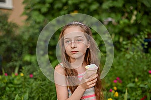 Little girl eat ice cream at an outdoor In a colorful striped bright dress. Sunny summer, hot weather