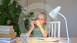 Little girl eating an apple during break lessons