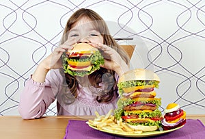 Little girl eating a big hamburger