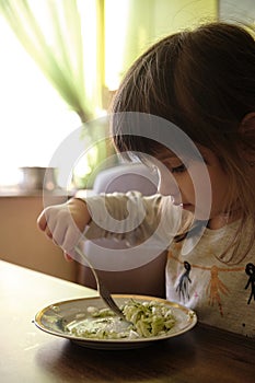 Little girl eating cabbage salad. Cut girl loves cabbage salad