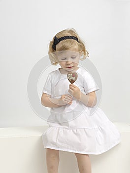 Little girl eating a chocolate lollypop