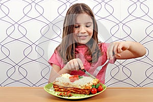 Little girl eating delicious lasagne