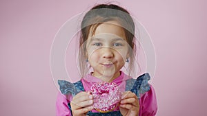 Little girl eating donut with sprinkles, smiles