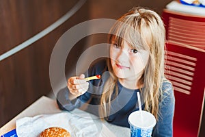 Little girl eating fast food in a cafe