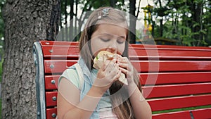 Little Girl Eating a Hamburger In the Park