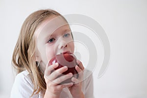 Little girl eating heartily fresh red apple
