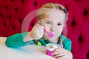 Little girl eating ice cream in cafe