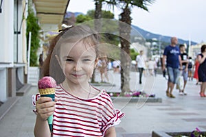 Little girl eating ice cream. A child on the street with berry ice cream.
