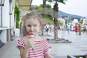 Little girl eating ice cream. A child on the street with berry ice cream.