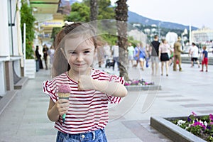 Little girl eating ice cream. A child on the street with berry ice cream.