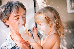 A little girl is eating ice cream sitting on her father`s should