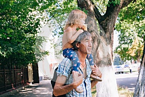 A little girl is eating ice cream sitting on her father`s should