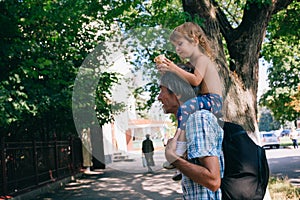 A little girl is eating ice cream sitting on her father`s should