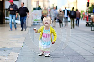 Little girl eating ice cream walking in the city