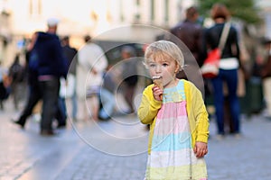 Little girl eating ice cream walking in the city