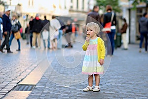 Little girl eating ice cream walking in the city