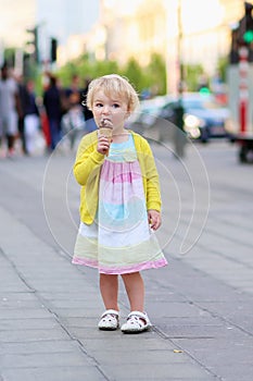 Little girl eating ice cream walking in the city