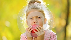 Little girl eating a natural apple ,outdoors . Little girl eating a natural apple in autumn Park. Healthily concept. Healthy