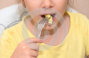 Little girl eating omelet with fork, close up