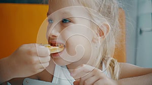 Little girl eating pizza in a fast food restaurant indoors, last piece. Funny little girl eating pizza and smiling at