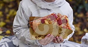 little girl eating pizza. Person holds pizza in hands and eats in the park in autumn. Street food concept, fast food in