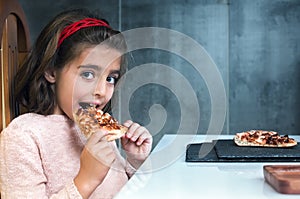 Little girl eating pizza in a restaurant photo