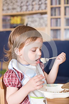 Little girl eating porridge at home photo