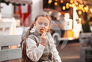 Little girl eating rench fries with sauce at street cafe outside. Concept of fast food and children